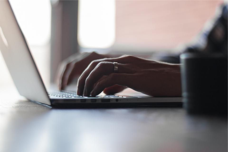 Close-up of hands working on a laptop